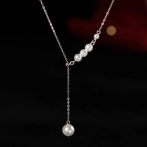 Collier élégant en argent avec perles et pendentif en forme de Y sur fond noir