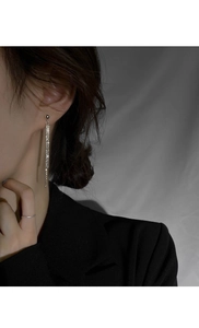 Détail de boucles d'oreilles pendantes à pompons argentés avec chaînes scintillantes