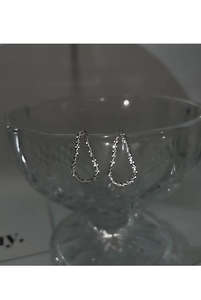 Gros plan de boucles d'oreilles argentées en forme de poire avec texture givrée