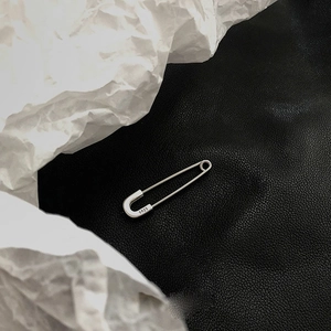 Pendientes de imperdible en plata S925 pulida sobre fondo de cuero y papel arrugado