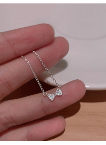 Gros plan d'un collier nœud en argent serti de zircons brillants tenu à la main