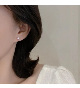 Primer plano de un pendiente de plata 925 con circón rosa en la oreja de modelo