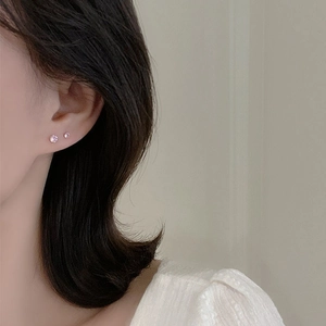 Pendientes minimalistas de plata 925 con circonita rosa en la oreja del modelo