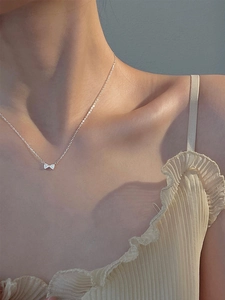 Détail du collier à pendentif nœud en argent avec zircons étincelants sur le cou du mannequin