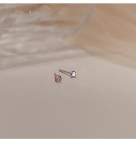 Detalle macro de pendientes minimalistas de circonita rosa con montura de plata de ley