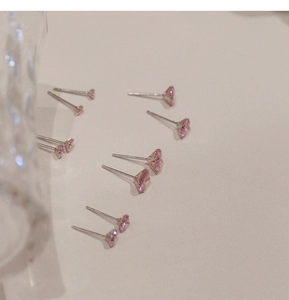 Detalle macro de pendientes de corazón con circón rosa y postes de plata 925 minimalistas