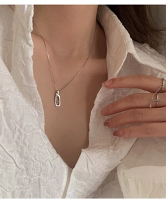 Nahaufnahme der ineinandergreifenden Ringkette und Zirkonringe auf weißem Hemd
