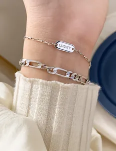 Detailansicht der silbernen Lucky-Anhänger und Figaro-Armbänder am gestrickten Ärmel