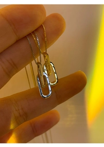 Detail von ineinandergreifenden Silber- und Goldketten mit Forever-Gravur und Kristallen