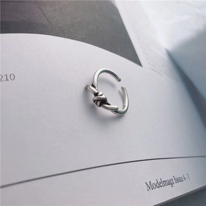Anillo abierto de plata S925 con diseño de nudo ajustable sobre una revista de moda