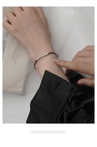 Primer plano de pulsera Mobius de plata pulida usada en la muñeca para un estilo elegante