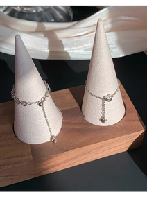 Detailed view of silver heart chain rings featuring delicate charms on a display stand
