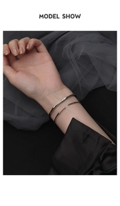 Detalle del brazalete Möbius plateado con diseño de onda líquida en la muñeca real
