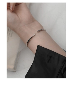 Detalle del sello de plata S925 en un brazalete abierto Möbius de diseño minimalista