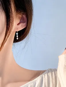 Close-up of three silver-plated heart pendants on a drop earring worn by a model