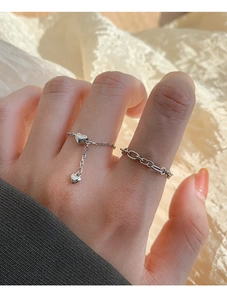 Macro view of silver heart pendant chain ring and oval link ring set on female finger