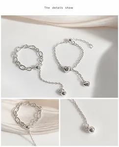 Detail of adjustable silver heart chain ring with beads on a satin background