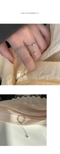 Detailed view of silver heart chain ring on beige satin with adjustable bead tassel