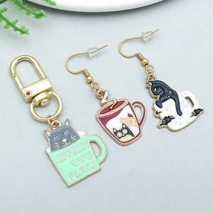 Detail of creative cat and coffee cup charms on a gold keychain and earring set