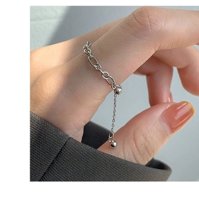 Detail view of adjustable silver heart chain ring with small bead charm on finger