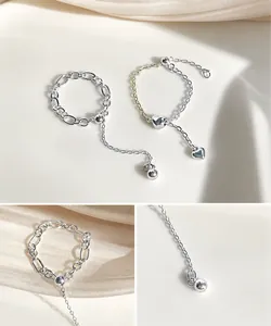 Detail of silver heart and bead charms on adjustable chain ring with silk background