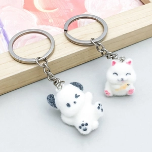 Gros plan de pendentifs panda et chat en peluche blanche avec porte-clés en métal