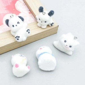 Gros plan de cinq pendentifs chiots floqués blancs avec anneaux en argent pour bijoux DIY