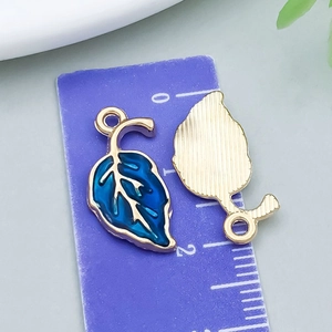 Détails macro des breloques feuilles d'érable en émail avec finition dorée et texture