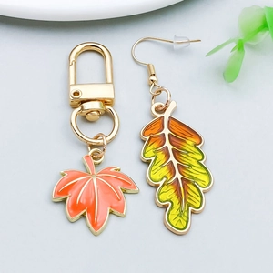 Détail du pendentif feuille d'érable en émail et boucle d'oreille d'automne dorée
