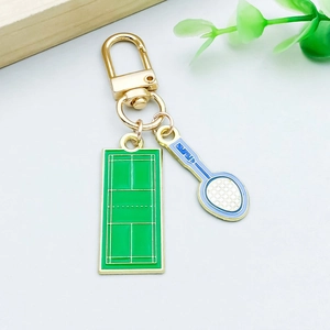Detail of gold metal keychain featuring green tennis court and racket charms