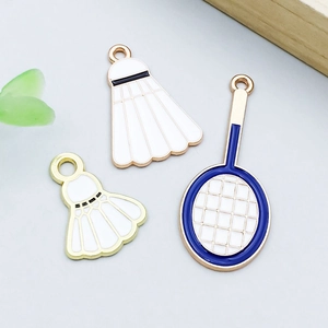 Detailed macro view of white enamel badminton and blue tennis racket charms for DIY jewelry