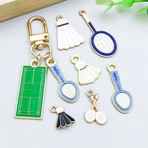 Detailed flat lay of white enamel shuttlecock and badminton court jewelry charms