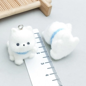 Macro view of 2cm mini flocked white dog pendants with blue collars and metal rings