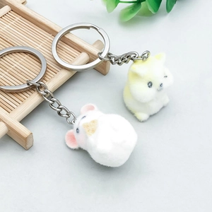Close-up of two colorful flocked cartoon puppy charms with silver metal keychains