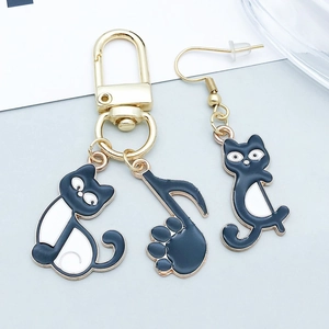 Detail von Katzen- und Musiknoten-Anhängern an Gold-Schlüsselanhänger und Ohrring-Set