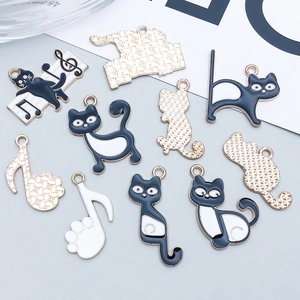 Makroaufnahme von schwarz-weißen Emaille-Katzen und Musiknoten-Anhängern für DIY-Schmuck