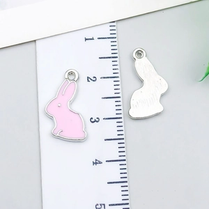 Pink enamel bunny alloy pendant showing dimensions with a ruler for DIY jewelry