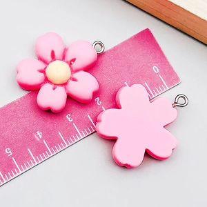 Detail view of pink resin flower charms with measurements and metal rings for DIY jewelry