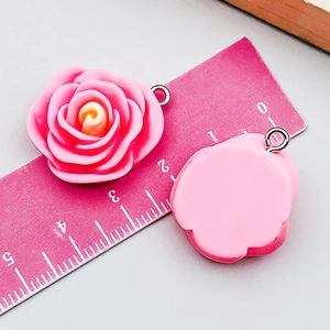 Macro detail of pink resin rose pendant with silver metal loop on measurement scale