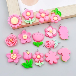 Macro view of assorted pink resin tulip and sunflower charms with metal rings for DIY jewelry