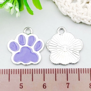 Macro view of purple enamel paw print charm showing front and back texture on a ruler