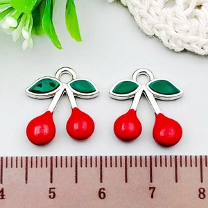 Close-up of red and green cherry charms with silver metal loops for DIY jewelry