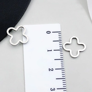 Close-up of 1.2cm hollow four-leaf clover stainless steel pendants on a scale ruler