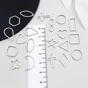 Assorted stainless steel geometric pendants like hearts and stars with ruler for scale