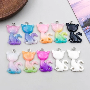Detailed flat lay of ten colorful glitter resin cat pendants with metallic rings
