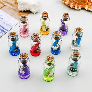 Détail de mini bouteilles à vœux en verre avec coquillages et liquide coloré pour bijoux