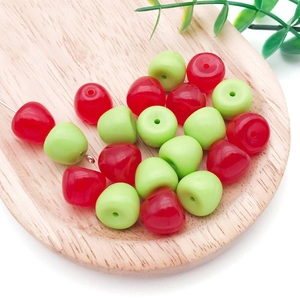 Detailed macro shot of red and green apple acrylic beads on a wooden display tray