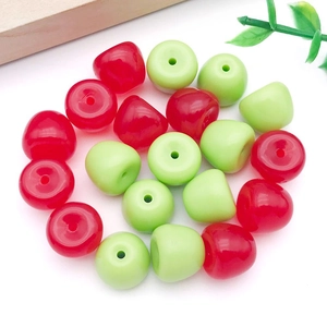 Detalle de colgantes de manzana en acrílico rojo y verde con agujeros para joyería DIY