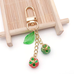 Detail of colorful glass clover and pumpkin charms on a golden lobster clasp keychain