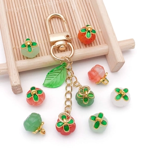 Detailed view of colorful persimmon pendants and DIY beads with green enamel leaves